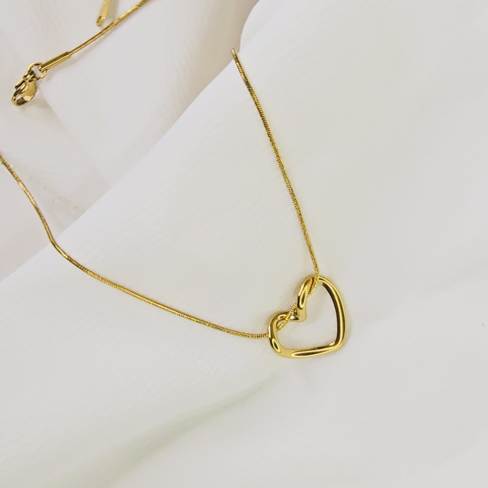 Video showing the smooth, three-dimensional curvature of the gold-plated twisted heart pendant.