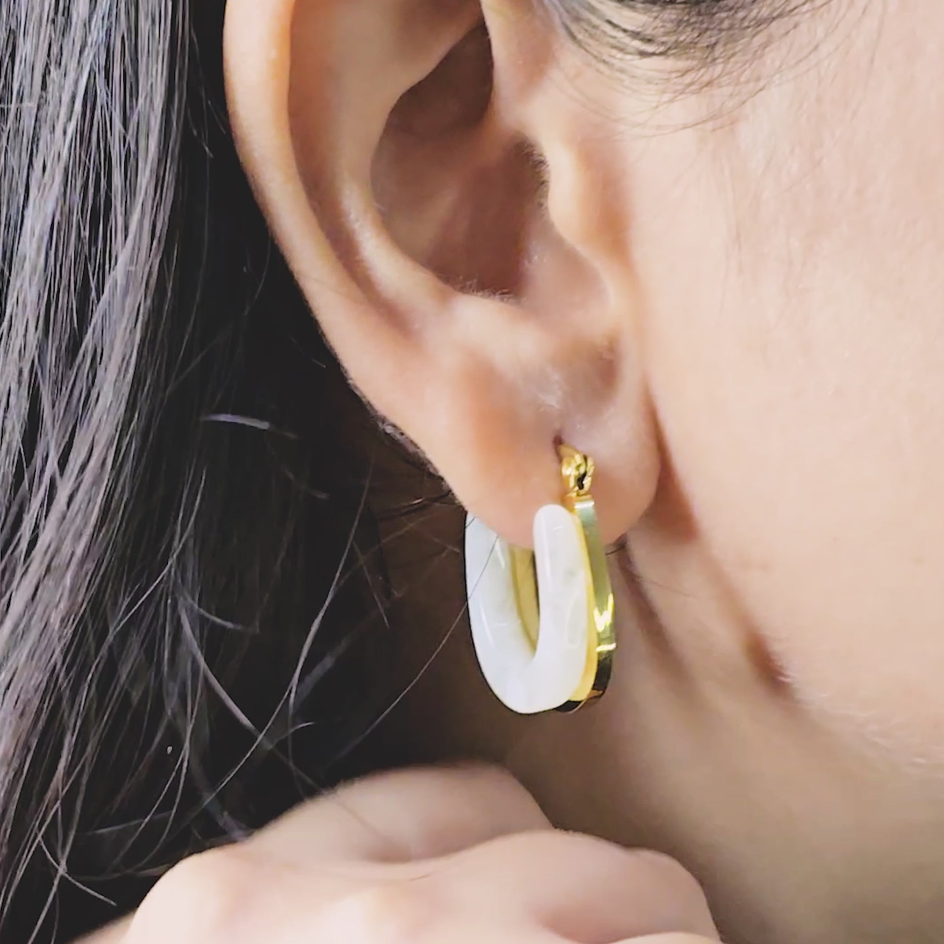 Moonlit Loop Earrings – close-up video of ivory and gold U-shaped hoops worn on model’s ear, showing glossy anti-tarnish finish and chic minimalist design.