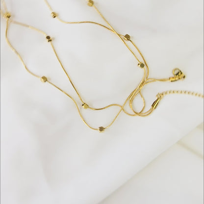 360-degree video of Loose Pixel Chain on white background showing gold-toned layered necklace with cube beads and reflective finish.