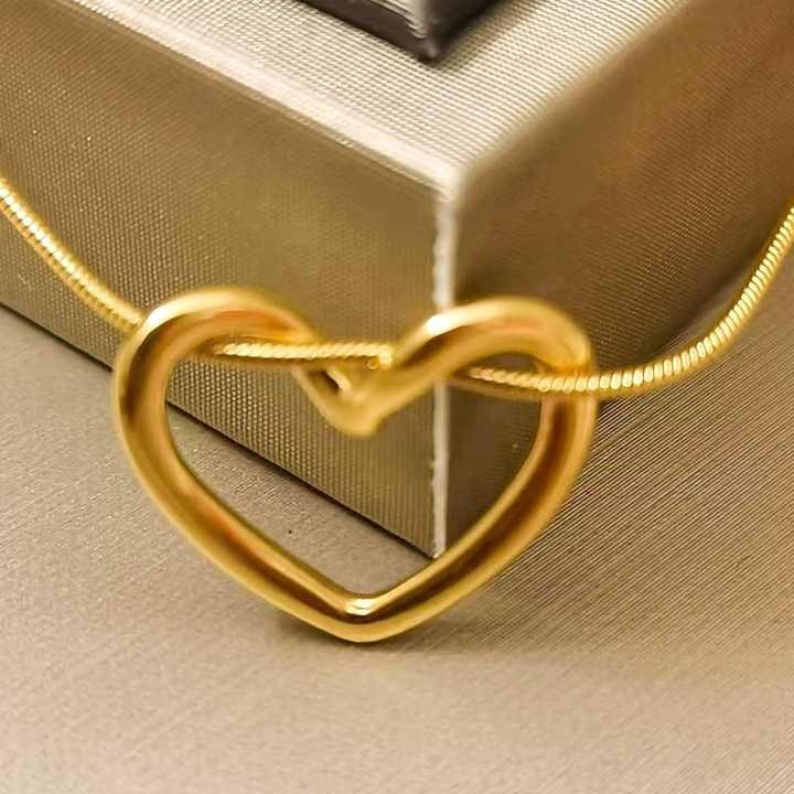 Zoomed-in view of twisted heart pendant – glossy gold detailing with luxurious background