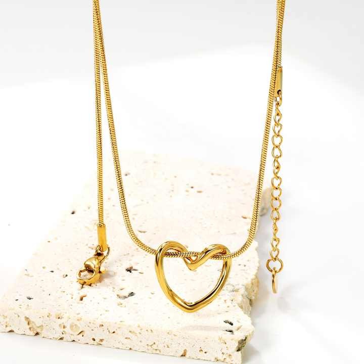 Close-up of Twisted Heart Necklace hanging – gold heart pendant with snake chain and adjustable clasp