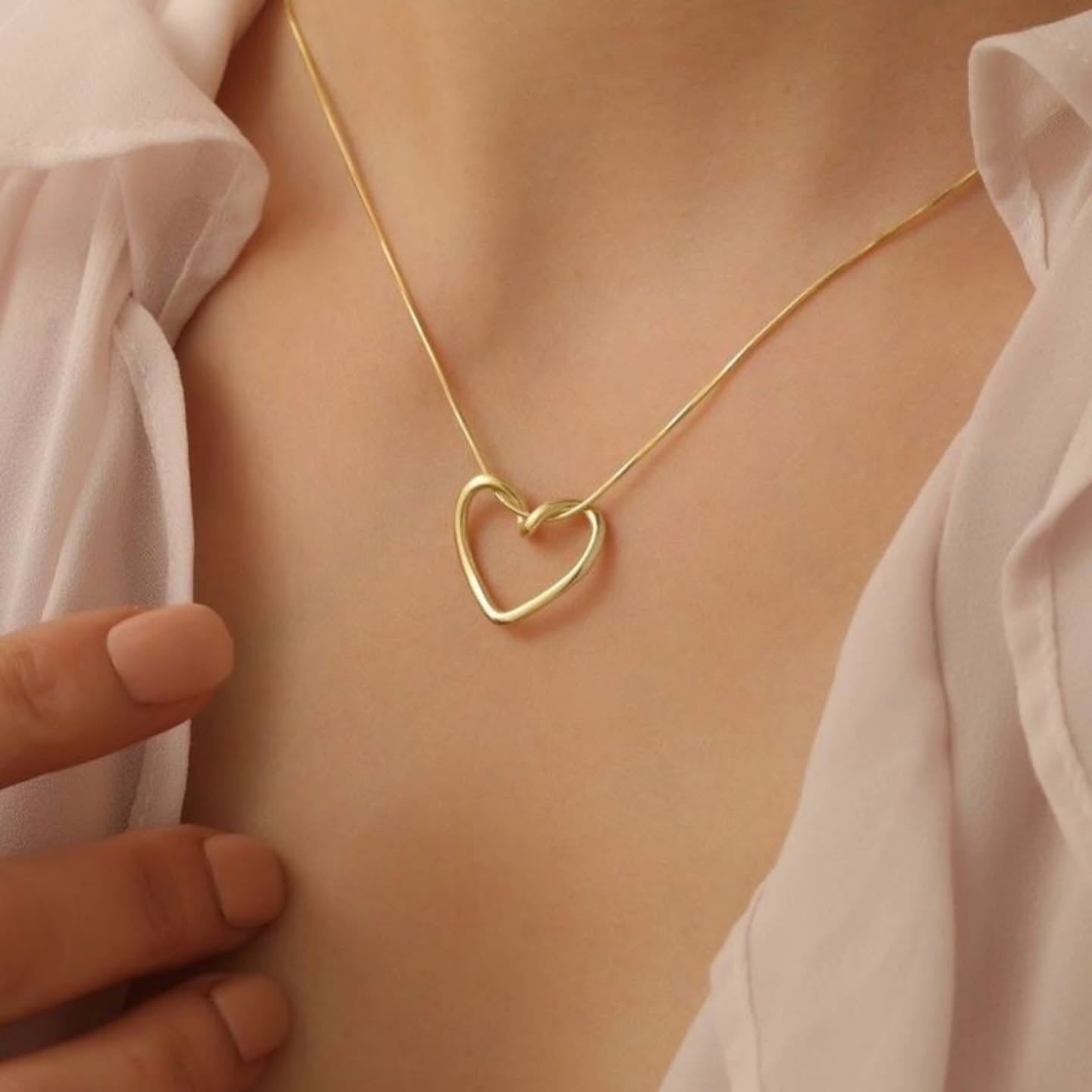 Model wearing the Twisted Heart Necklace – minimalist gold heart pendant resting on collarbone